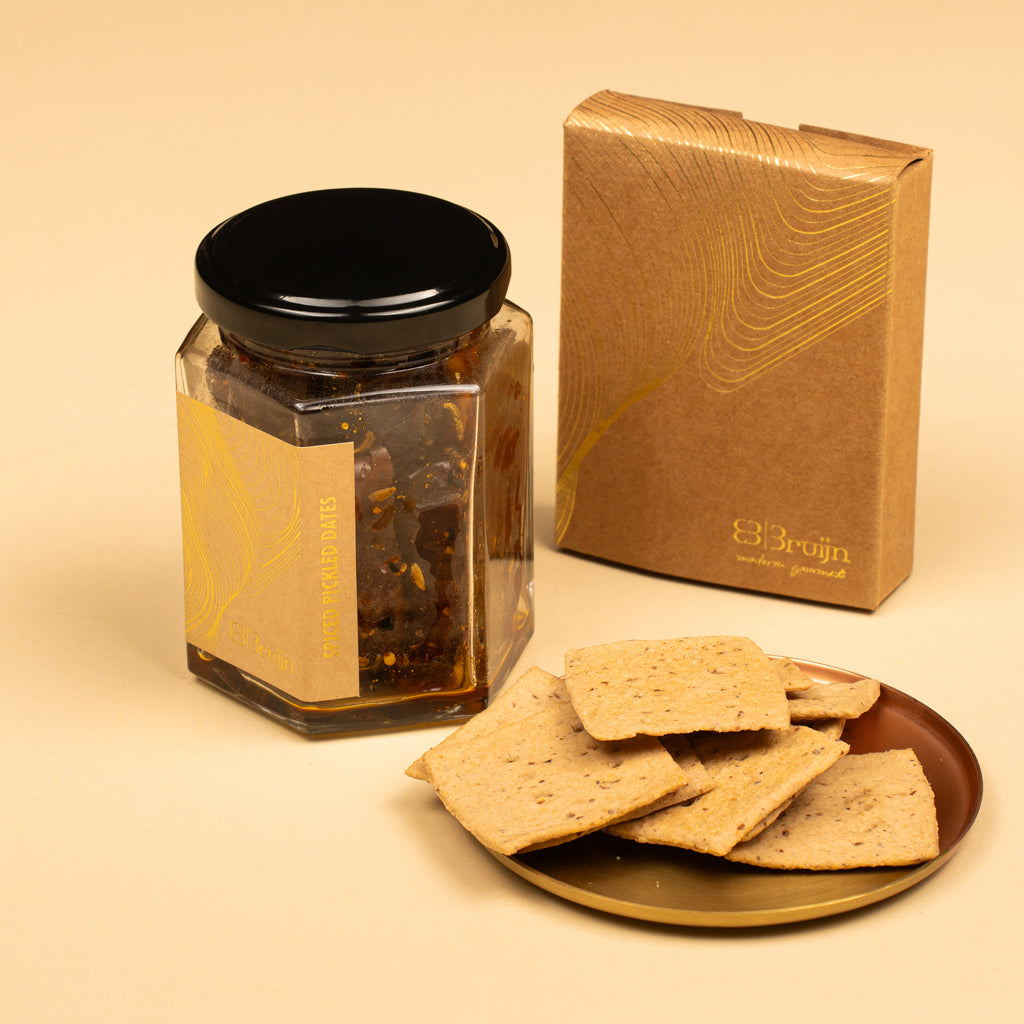 Jar of spiced date pickle and here ajwain crackers on a beige background