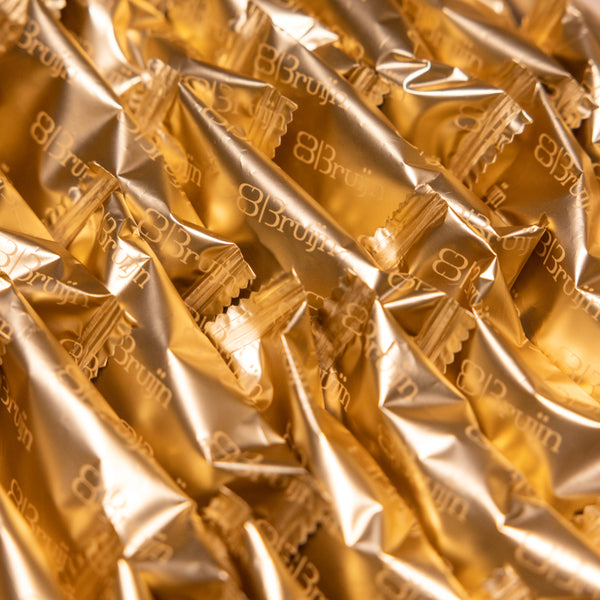 Detailed view of Bruijn golden-foil wrapped Medjool dates stacked in tray.