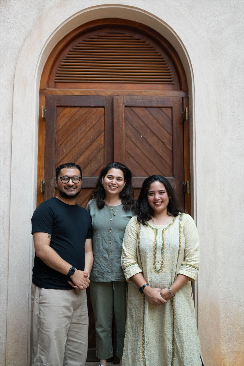 Three people standing in front of a wooden door.