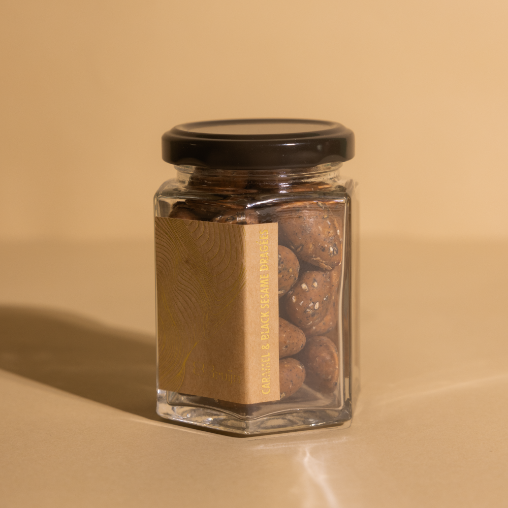 Black sesame and caramelised white chocolate coated almond dragees in a glass jar