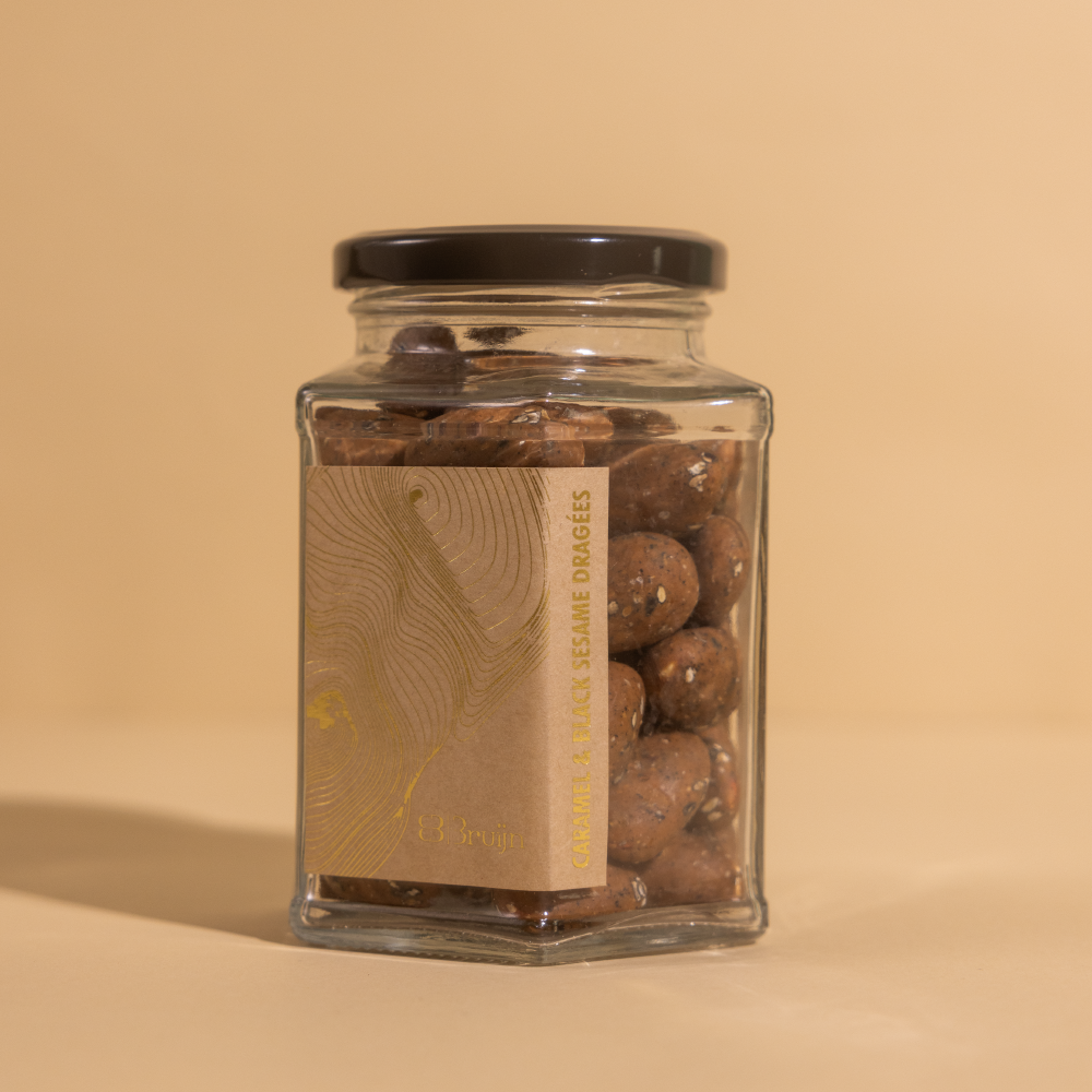 Black sesame and caramelised white chocolate coated almond dragees in a glass jar