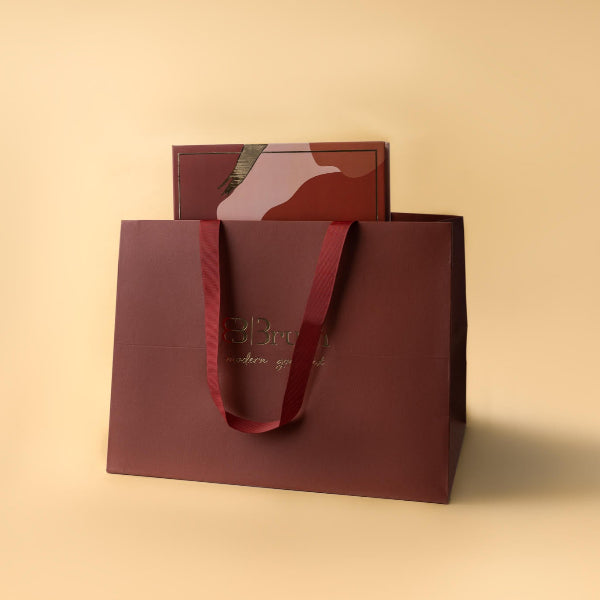 Maroon gift bag with red handle on a beige background