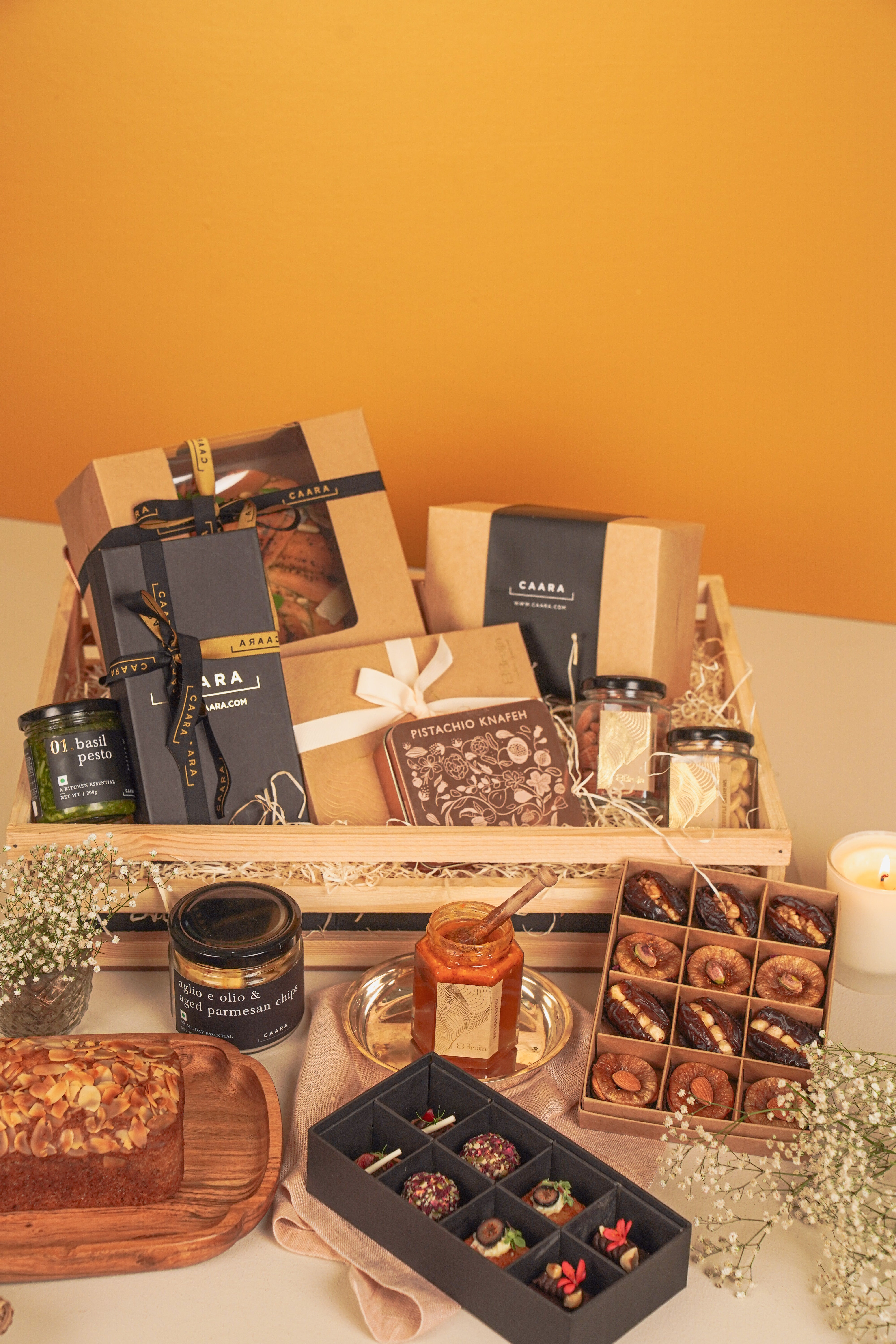 Assorted gift items including boxes, jars, and a tray with snacks on a wooden shelf 
