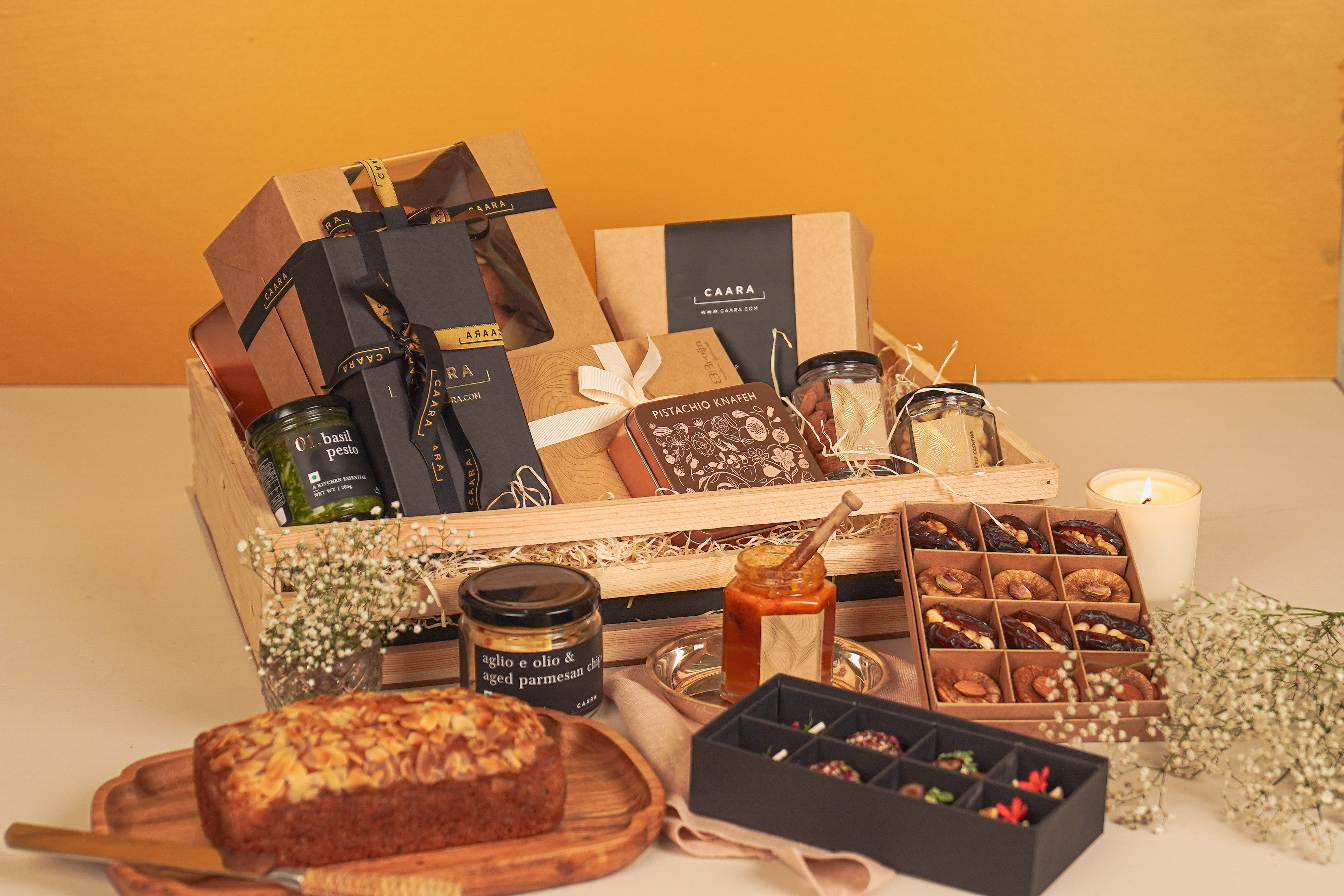 Gourmet gift basket with chocolate, bread, and candles on a table.