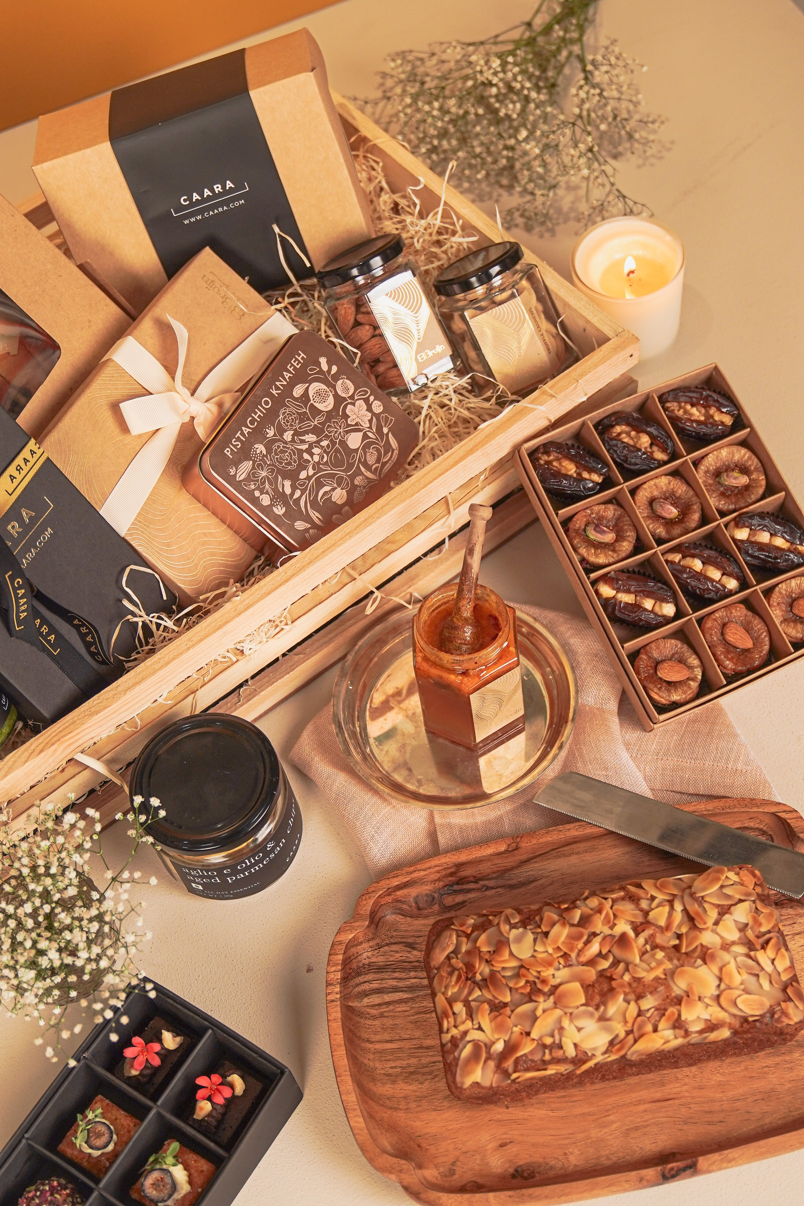 Gourmet food platter with assorted treats, candles, and a loaf of bread on a wooden tray.
