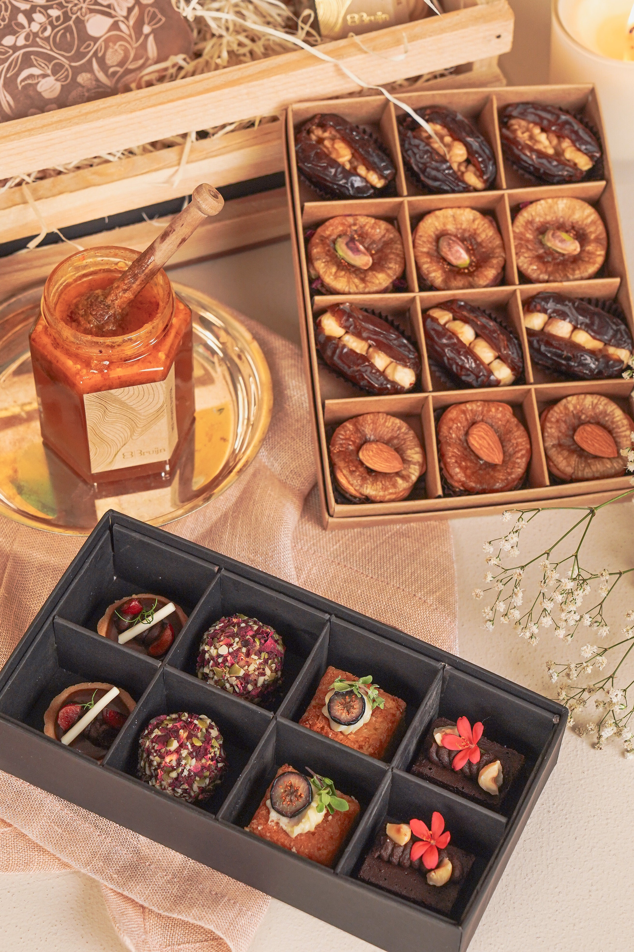 Two boxes of assorted dried fruits and honey on a decorative table setting.