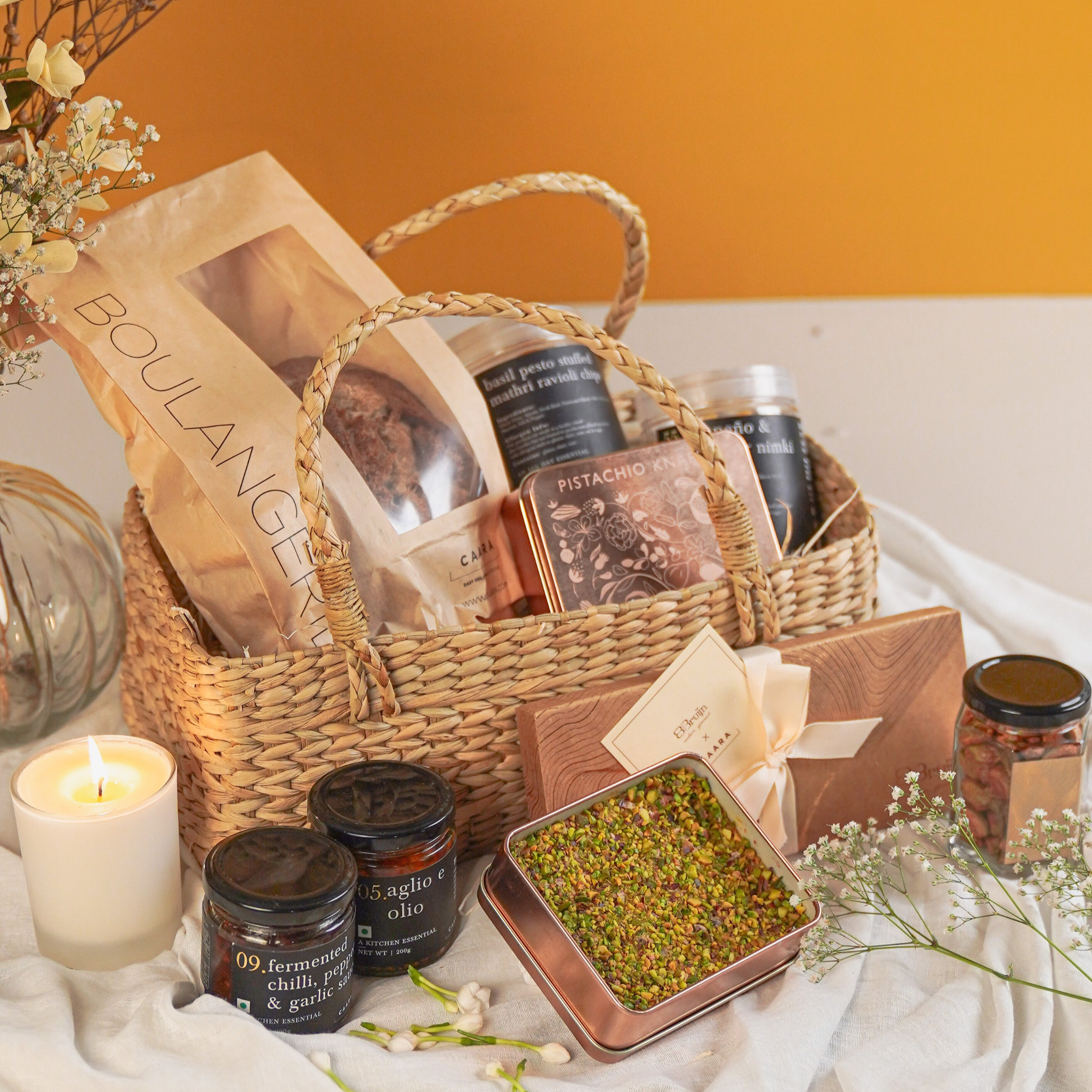Wicker basket with various items including jars and a candle 