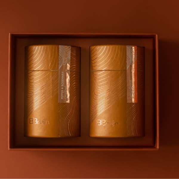 Two 100 gm cylindrical paper gift boxes, containing flavoured nuts.