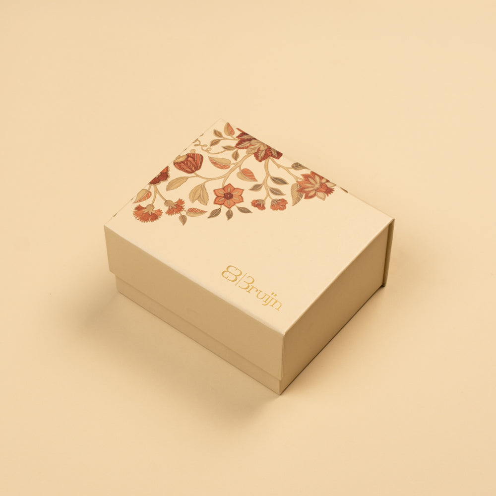 A square cream-colored gift box with a floral pattern on the lid and the brand name 'Bruijn' printed in gold, set against a solid cream background.