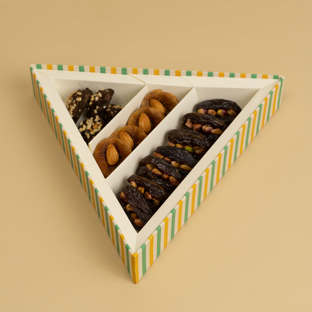 A triangle box that contains stuffed dates, stuffed figs, chocolate rocks 