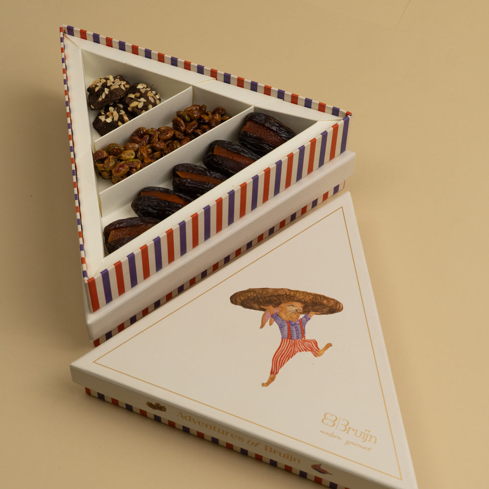 A triangle box that contains stuffed dates, honey and nut clusters, chocolate rocks 